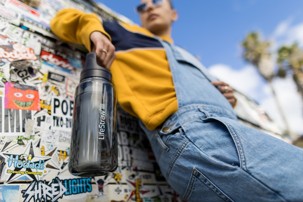 Mężczyzna prezentuje butelkę LifeStraw Go 2.0 w czarnym wariancie kolorystycznym w miejskim otoczeniu