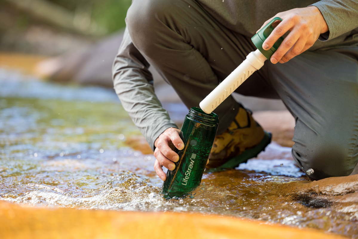 Mężczyzna napełnia butelkę LifeStraw Go 2.0 wodą z górskiego strumienia